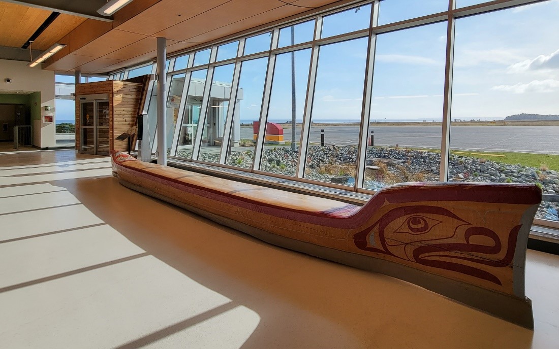 Banc fait d’un canot installé dans l’aérogare de l’aéroport de Port Hardy (YZT), sculpté par le sculpteur kwagul Mervyn Child