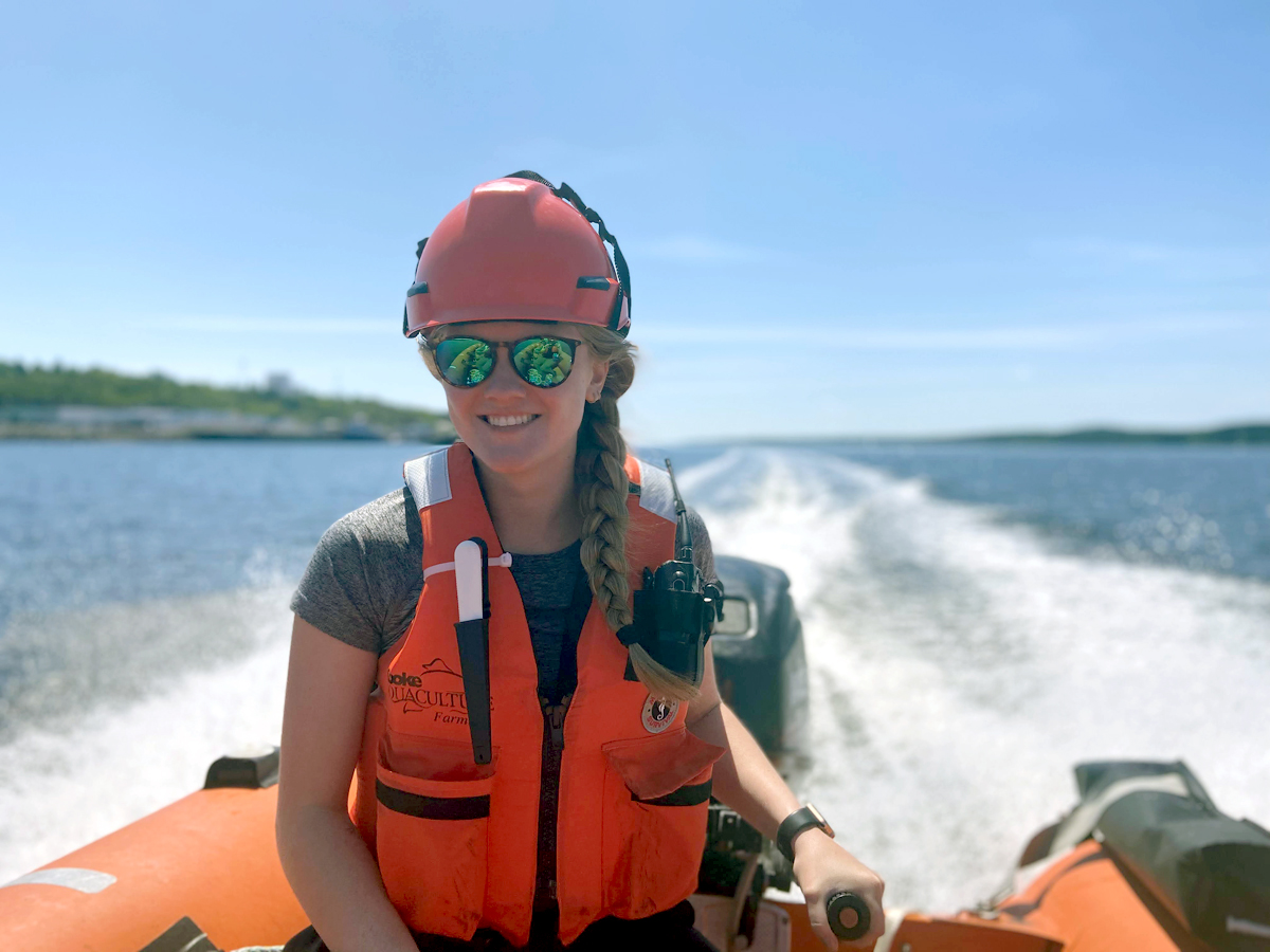 Lauryn Delaney, Marine Training Program Graduate, steers an orange boat through an open body of water.
