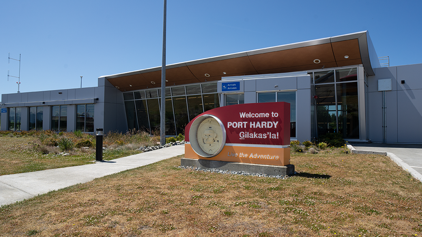 Front entrance of Port Hardy Airport. A sign reads, “Welcome to Port Hardy, live the adventure.”