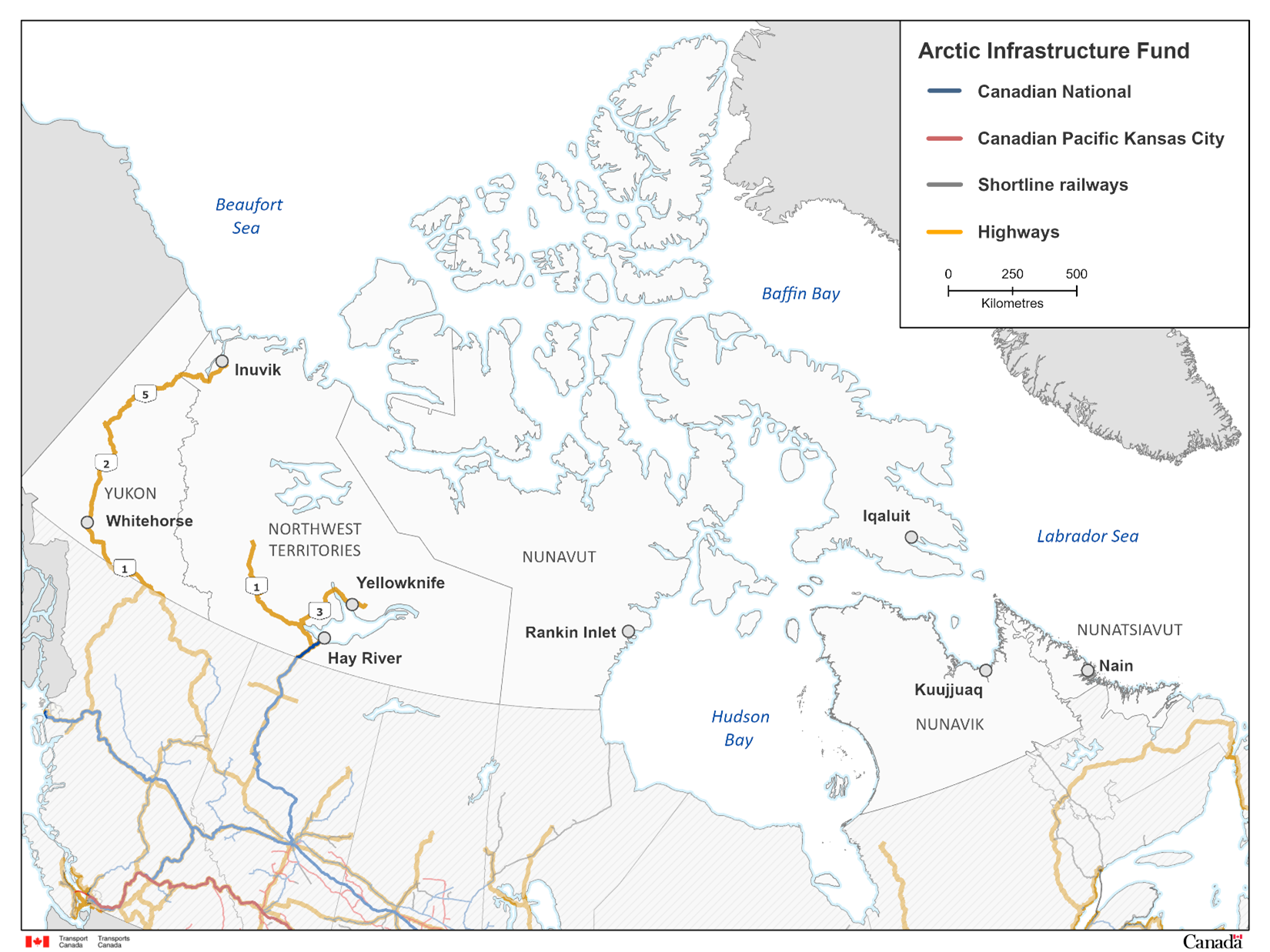 Carte du Nord canadien montrant les réseaux de transport admissibles dans le cadre du Fonds pour l’infrastructure de l’Arctique. La carte présente les principales lignes ferroviaires, Canadien National (bleu), Canadien Pacifique Kansas City (rouge) et chemins de fer d’intérêt local (gris), ainsi que les autoroutes (orange). Elle illustre le Yukon, les Territoires du Nord‑Ouest, le Nunavut et les régions nordiques du Québec et du Labrador, avec plusieurs collectivités clés identifiées, dont Whitehorse, Inuvik, Yellowknife, Hay River, Rankin Inlet, Iqaluit, Kuujjuaq et Nain. Les étendues d’eau environnantes comme la mer de Beaufort, la baie de Baffin, la baie d’Hudson et la mer du Labrador sont également indiquées. La légende en haut à droite explique le code de couleur, et la carte comprend une échelle de distance.
